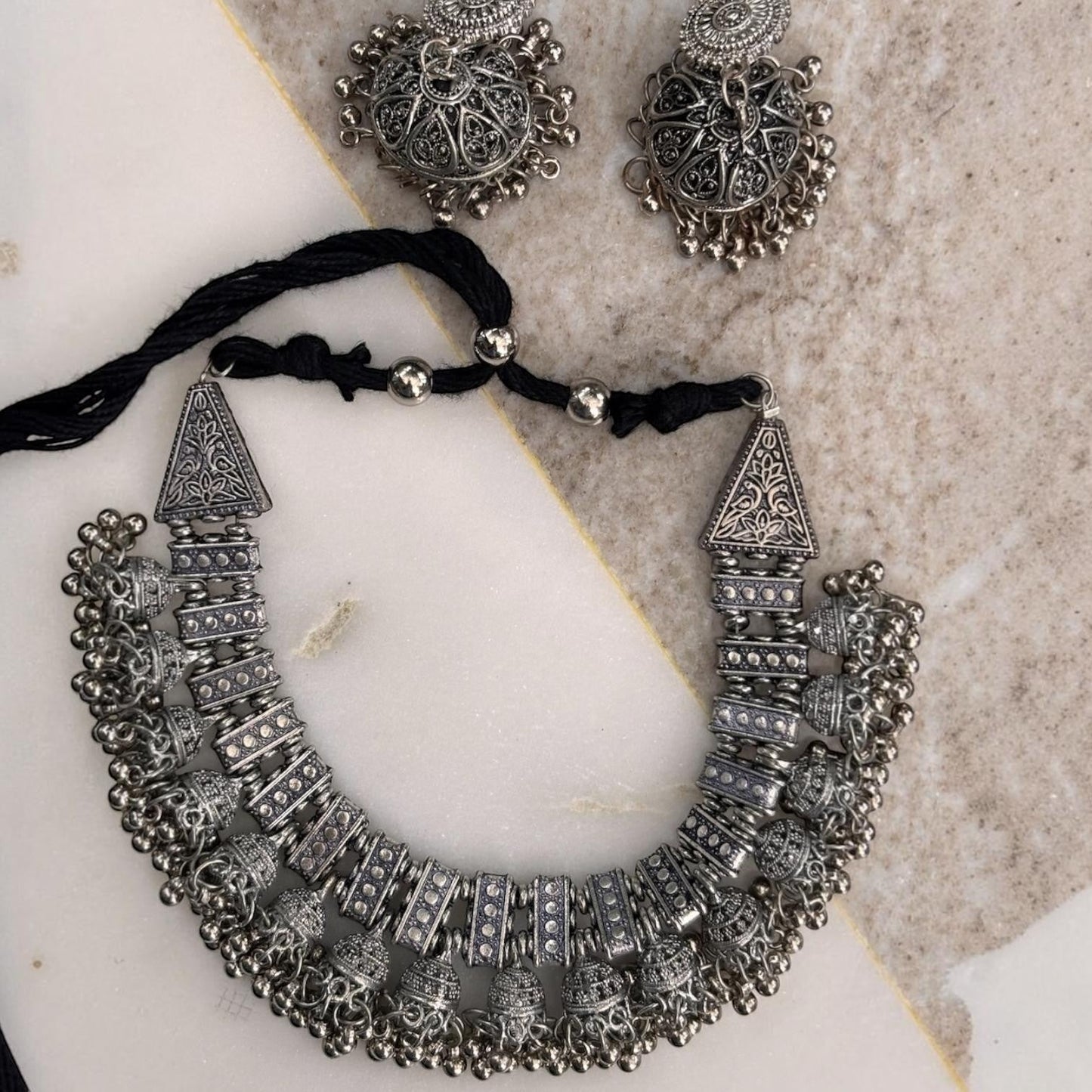 Gapochi oxidised silver tribal choker necklace and matching jhumki earrings with intricate filigree and bead details.